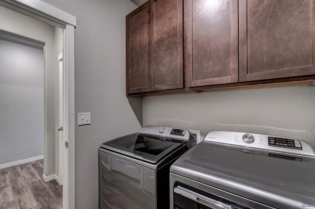 clothes washing area featuring cabinets, hardwood / wood-style floors, and washing machine and dryer