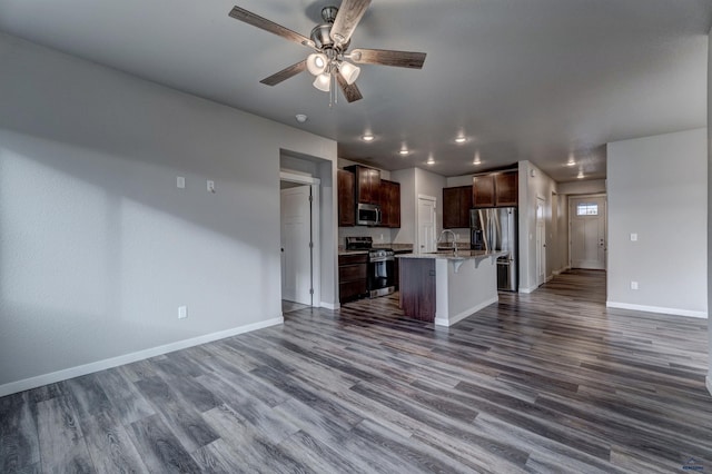 kitchen featuring a kitchen bar, dark hardwood / wood-style flooring, stainless steel appliances, and a kitchen island with sink