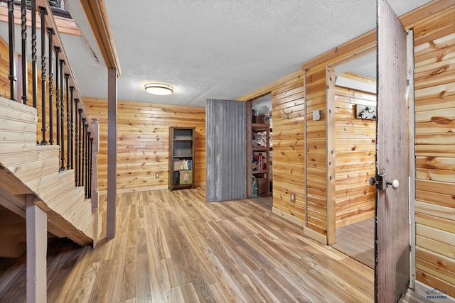 interior space featuring wooden walls, wood-type flooring, and a textured ceiling