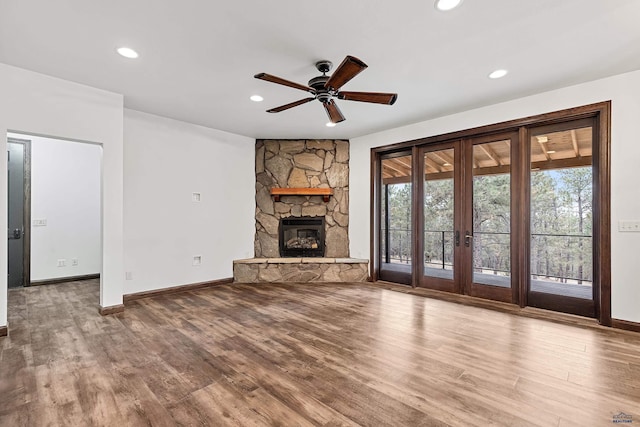 unfurnished living room featuring a fireplace, french doors, hardwood / wood-style flooring, and ceiling fan