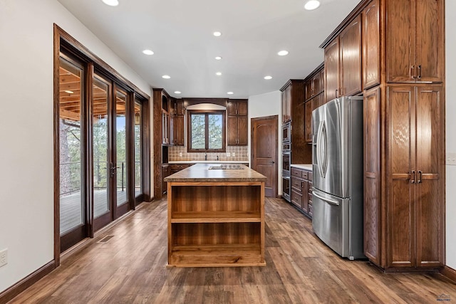 kitchen with decorative backsplash, a center island, stainless steel refrigerator, and plenty of natural light