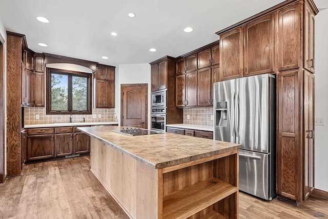 kitchen with tasteful backsplash, a center island, stainless steel appliances, and light hardwood / wood-style flooring