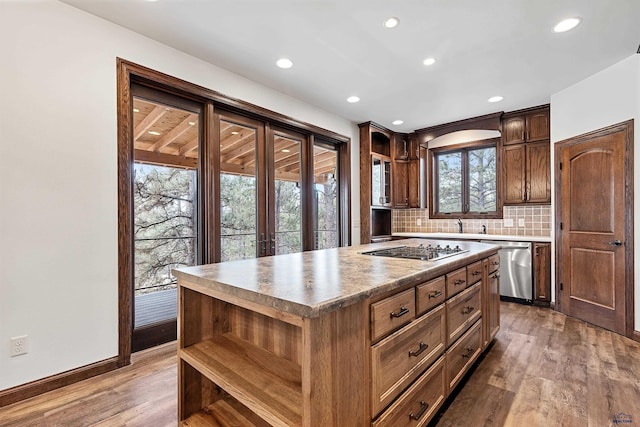 kitchen featuring tasteful backsplash, stainless steel dishwasher, hardwood / wood-style floors, black stovetop, and a kitchen island