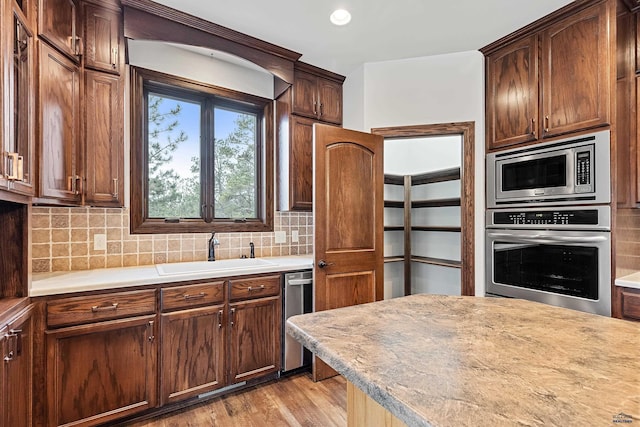 kitchen featuring stainless steel appliances, light hardwood / wood-style flooring, tasteful backsplash, and sink