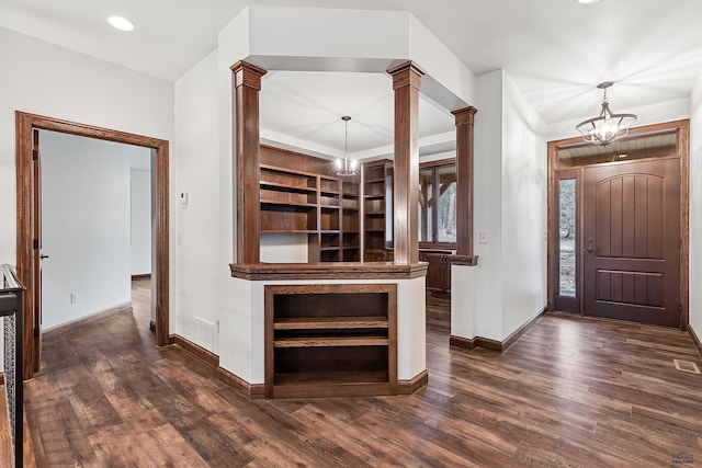 foyer with a chandelier, dark hardwood / wood-style flooring, and ornate columns