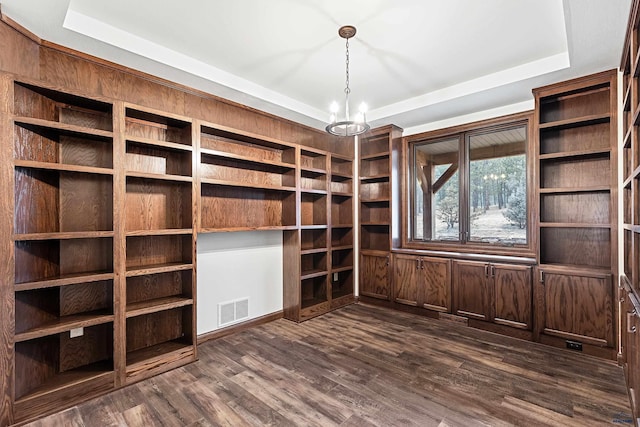 unfurnished office featuring a chandelier, a raised ceiling, and dark wood-type flooring