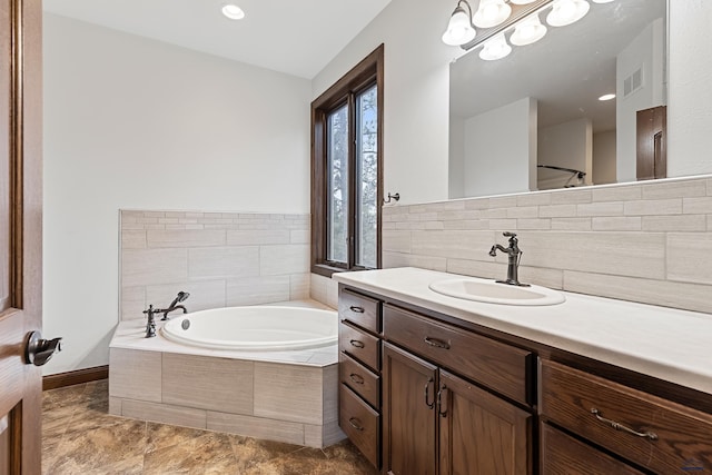 bathroom with tile patterned floors, tiled tub, and vanity