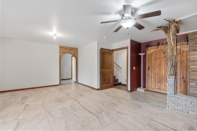 unfurnished room featuring a barn door and ceiling fan