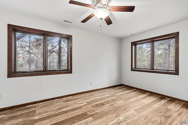 unfurnished room with a wealth of natural light, ceiling fan, and light hardwood / wood-style flooring