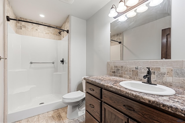 bathroom with vanity, backsplash, toilet, and walk in shower