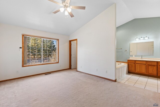 unfurnished bedroom with ensuite bathroom, sink, vaulted ceiling, ceiling fan, and light colored carpet