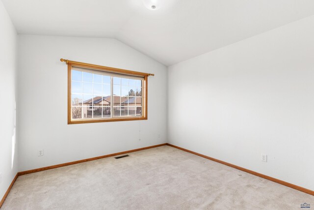 carpeted spare room with vaulted ceiling