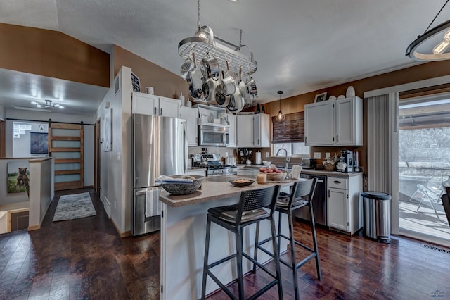 kitchen featuring white cabinets, pendant lighting, and a barn door