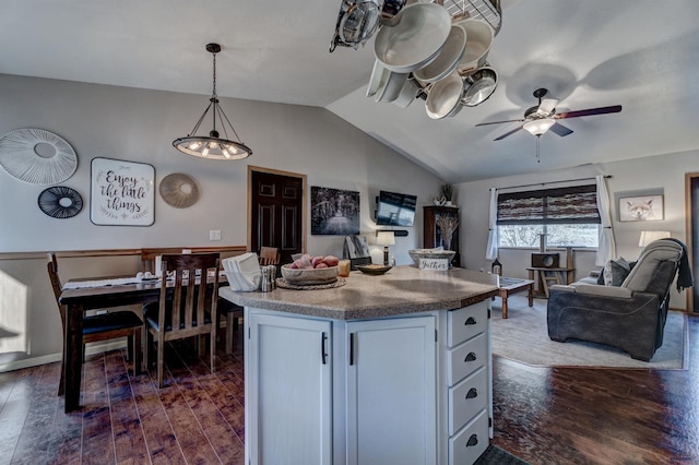 kitchen with hanging light fixtures, vaulted ceiling, dark hardwood / wood-style floors, ceiling fan, and white cabinetry