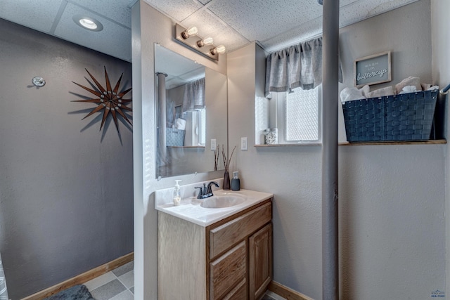 bathroom with a paneled ceiling and vanity