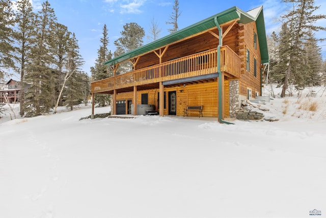 snow covered back of property with a wooden deck