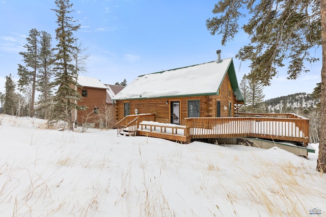 snow covered back of property featuring a deck