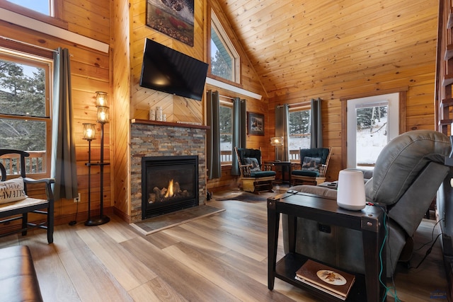 living room featuring a wealth of natural light, light wood-type flooring, a fireplace, and high vaulted ceiling