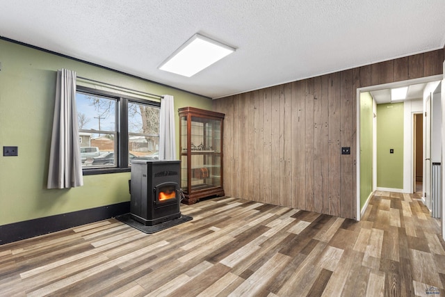 210 E Montana, Rapid City, SD 57701 - empty room featuring light wood-style floors, a wood stove, a textured ceiling, and wooden walls