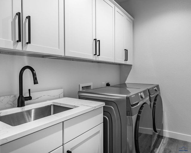 laundry room featuring cabinets, wood-type flooring, washing machine and clothes dryer, and sink