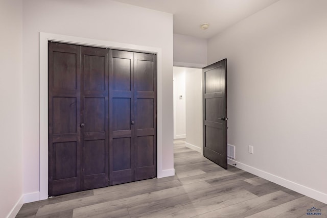 unfurnished bedroom with a closet and light wood-type flooring