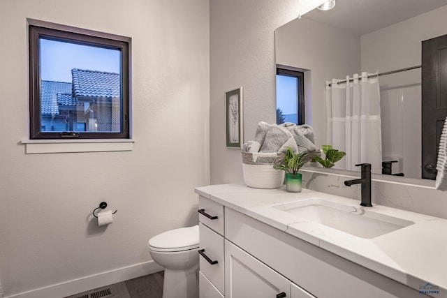 bathroom with hardwood / wood-style flooring, vanity, curtained shower, and toilet