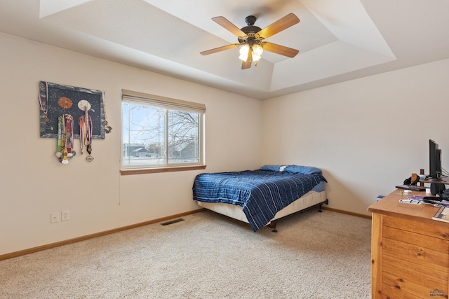 bedroom featuring a raised ceiling, ceiling fan, and carpet flooring