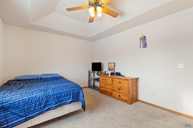 carpeted bedroom with ceiling fan and a tray ceiling