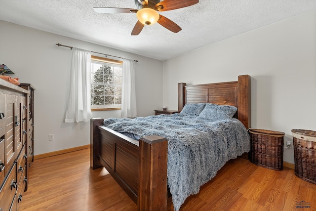 bedroom with a textured ceiling, light wood-type flooring, and ceiling fan