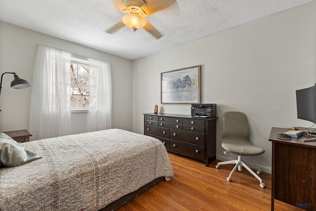 bedroom with ceiling fan, light hardwood / wood-style floors, and a textured ceiling