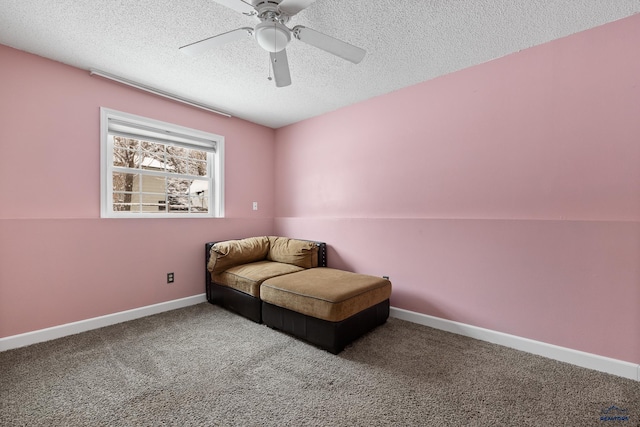 living area with ceiling fan, carpet floors, and a textured ceiling