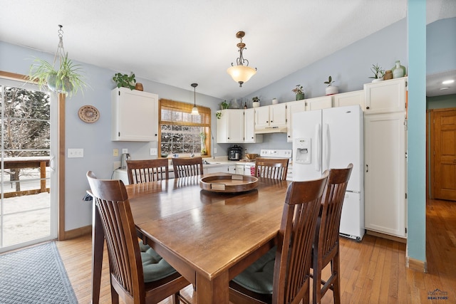 dining room with light hardwood / wood-style flooring and vaulted ceiling