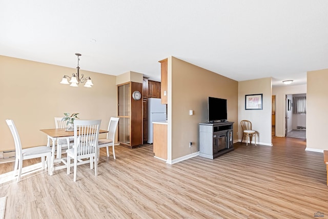 kitchen with white fridge, light wood-type flooring, hanging light fixtures, and an inviting chandelier