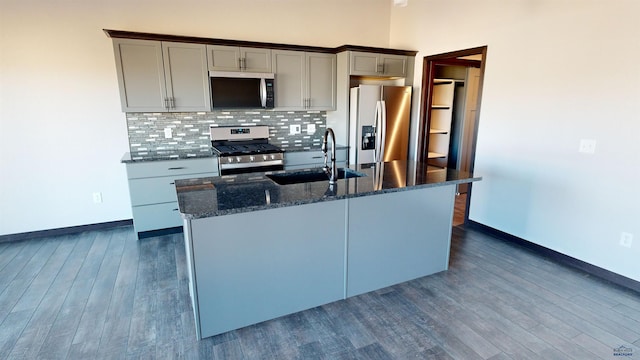 kitchen featuring decorative backsplash, gray cabinetry, stainless steel appliances, sink, and dark stone countertops