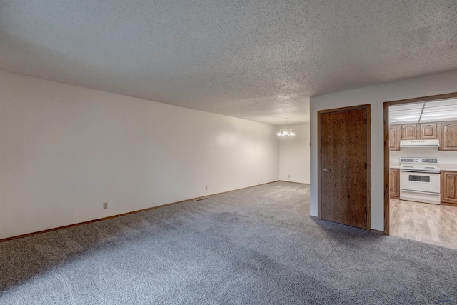 unfurnished room with light carpet, a textured ceiling, and a notable chandelier