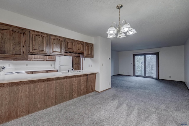 kitchen featuring white refrigerator, a chandelier, pendant lighting, light colored carpet, and range