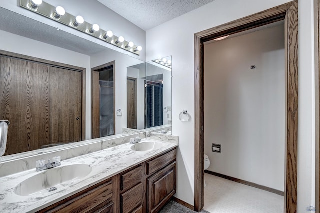 bathroom featuring tile patterned flooring, vanity, a textured ceiling, and toilet