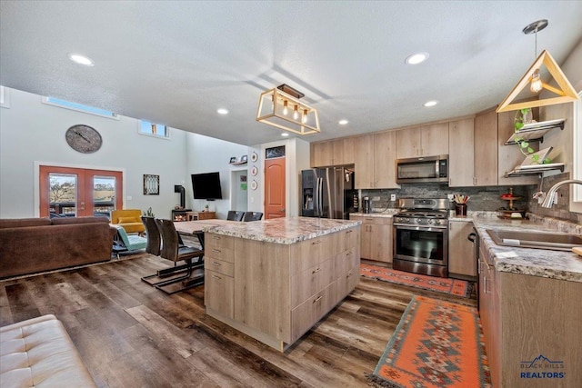 kitchen with hanging light fixtures, sink, light brown cabinetry, appliances with stainless steel finishes, and a kitchen island