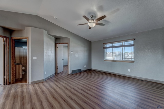 interior space featuring hardwood / wood-style flooring, ceiling fan, lofted ceiling, and ensuite bath