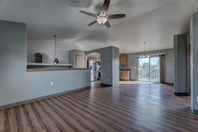 unfurnished living room featuring ceiling fan with notable chandelier, dark hardwood / wood-style flooring, lofted ceiling, and a textured ceiling