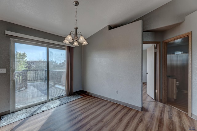 unfurnished dining area featuring hardwood / wood-style floors, lofted ceiling, and a chandelier