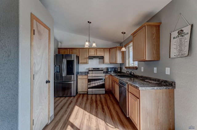 kitchen with appliances with stainless steel finishes, vaulted ceiling, sink, light brown cabinets, and hanging light fixtures