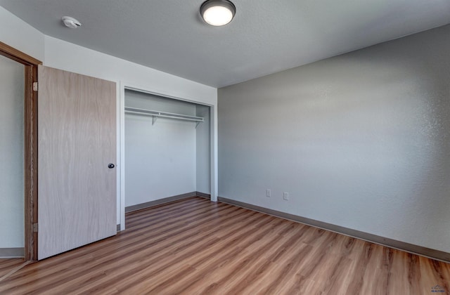 unfurnished bedroom featuring hardwood / wood-style flooring, a textured ceiling, and a closet