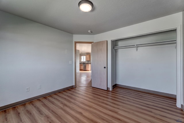 unfurnished bedroom featuring a closet, wood-type flooring, and a textured ceiling