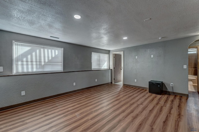 unfurnished living room featuring wood-type flooring, a textured ceiling, and a wealth of natural light