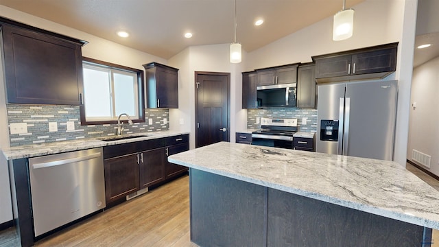 kitchen featuring stainless steel appliances, hanging light fixtures, lofted ceiling, and sink