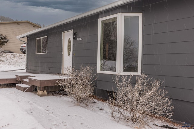 snow covered property entrance featuring a deck