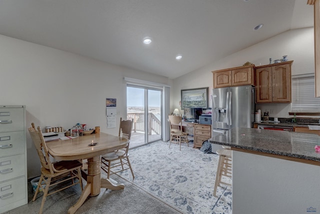 kitchen featuring dark stone countertops, stainless steel appliances, and vaulted ceiling