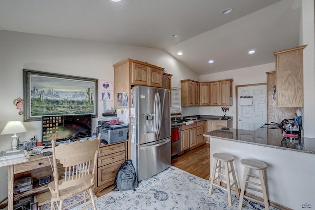 kitchen featuring lofted ceiling, dark stone counters, light hardwood / wood-style flooring, kitchen peninsula, and stainless steel appliances