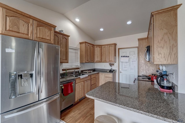 kitchen with kitchen peninsula, stainless steel appliances, sink, dark stone countertops, and lofted ceiling